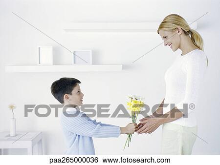 Boy holding out flowers to mother View Large Photo Image Stock Photograph - Boy holding out flowers to mother. Fotosearch