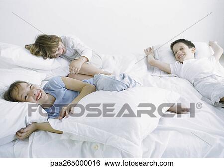 Boys and girl lying on bed laughing and smiling View Large Photo Image Stock Photograph - Boys and girl lying on bed laughing and smiling. Fotosearch