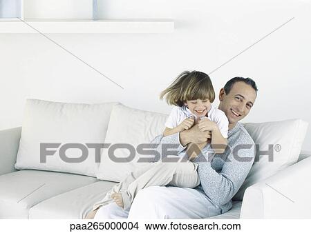 Father holding son on sofa View Large Photo Image Picture - Father holding son on sofa. Fotosearch