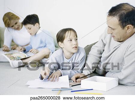Girl and father on floor, drawing, mother and boy in background reading View Large Photo Image Stock Photo - Girl and father on floor, drawing, mother and boy in background reading. Fotosearch