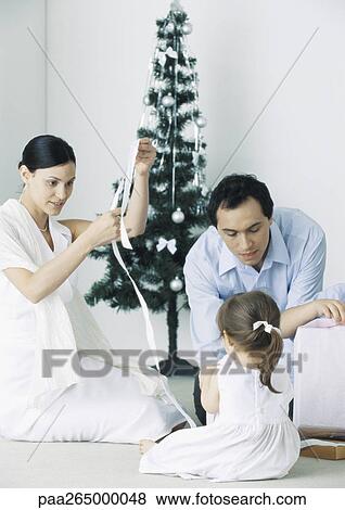 Little girl sitting on floor with parents near Christmas tree View Large Photo Image Stock Photo - Little girl sitting on floor with parents near Christmas tree. Fotosearch