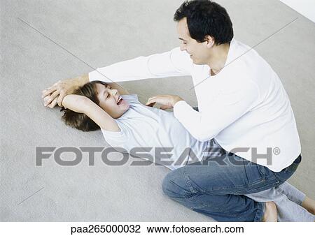 Man tickling boy on floor View Large Photo Image Stock Image - Man tickling boy on floor. Fotosearch