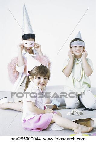 Mother sitting on floor with boy and girl, wearing party hats and disguises View Large Photo Image Picture - Mother sitting on floor with boy and girl, wearing party hats and disguises. Fotosearch