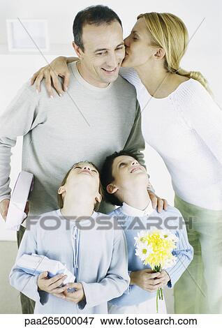 Woman kissing man on cheek, girl and boy looking up with heads back View Large Photo Image Stock Photo - Woman kissing man on cheek, girl and boy looking up with heads back. Fotosearch