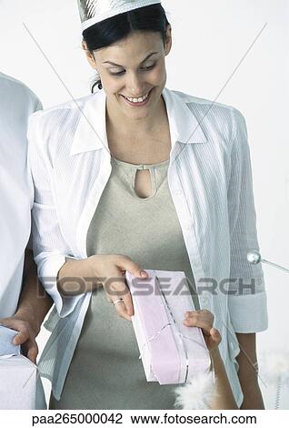 Stock Image - Woman wearing party hat receiving gift from daughter. Fotosearch