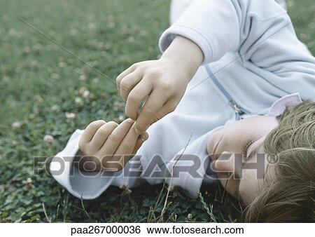 Boy lying on grass holding fingers together in front of face View Large Photo Image Stock Photograph - Boy lying on grass holding fingers together in front of face. Fotosearch