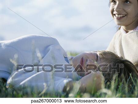 Boy lying on grass with eyes closed, girl behind him View Large Photo Image Stock Image - Boy lying on grass with eyes closed, girl behind him. Fotosearch