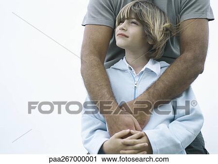 Boy standing with father's arms around him View Large Photo Image Stock Image - Boy standing with father's arms around him. Fotosearch