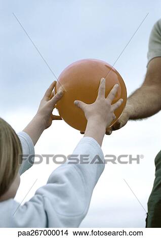 Picture - Boy taking ball from father, partial view. Fotosearch
