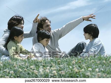 Boys and girl sitting on grass with parents pointing View Large Photo Image Stock Photo - Boys and girl sitting on grass with parents pointing. Fotosearch