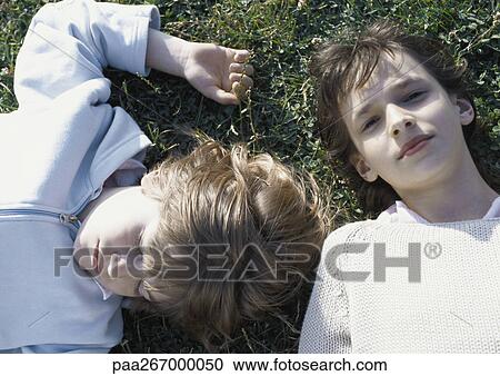 Stock Image - Girl and boy lying on grass. Fotosearch