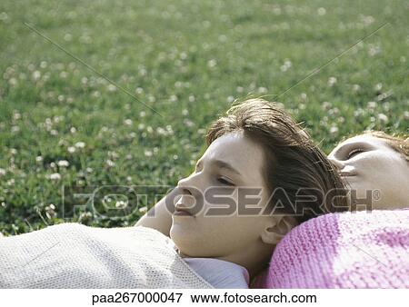 Stock Photo - Girl and mother lying on grass. Fotosearch