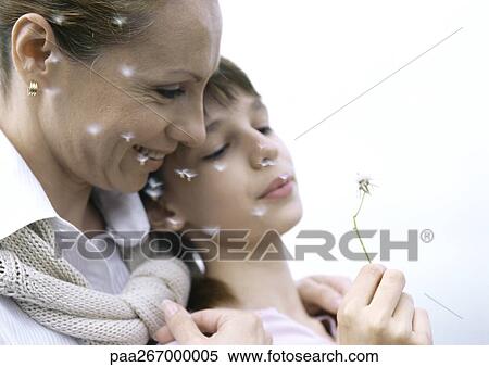 Stock Photography - Mother with girl blowing dandelion seeds, close-up. Fotosearch