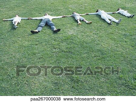 Parents with boys and girl lying on backs on grass with arms out, holding hands View Large Photo Image Stock Photo - Parents with boys and girl lying on backs on grass with arms out, holding hands. Fotosearch