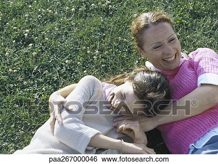 Stock Photograph - Woman and daughter lying on grass laughing. Fotosearch