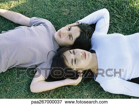 Stock Photo - Woman and son lying on grass head to head. Fotosearch