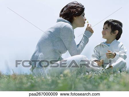 Woman and son sitting on grass, woman smelling flower View Large Photo Image Stock Photo - Woman and son sitting on grass, woman smelling flower. Fotosearch