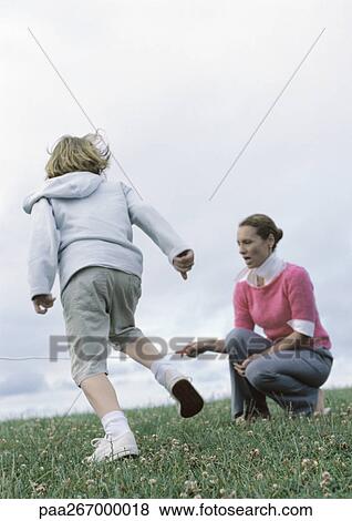 Stock Photo - Woman crouching holding end of jump rope for boy preparing to jump. Fotosearch