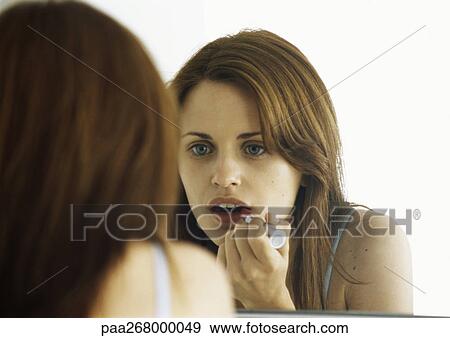 Woman applying lipstick in mirror View Large Photo Image Stock Photo - Woman applying lipstick in mirror. Fotosearch