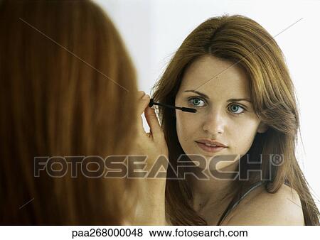 Stock Photo - Woman applying mascara in mirror. Fotosearch