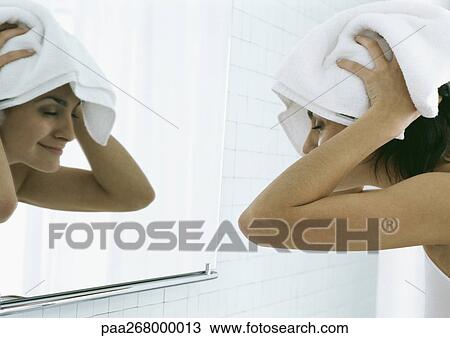Woman drying hair with towel in front of mirror View Large Photo Image Stock Image - Woman drying hair with towel in front of mirror. Fotosearch