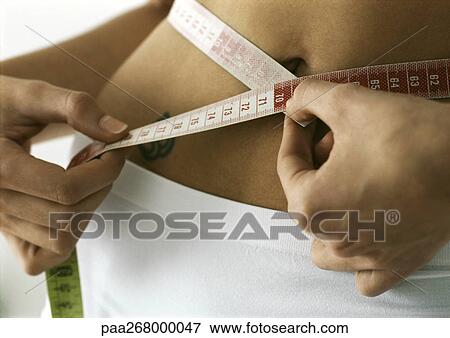 Woman measuring waist, close-up View Large Photo Image Stock Photo - Woman measuring waist, close-up. Fotosearch