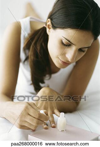 Woman polishing nails on bed View Large Photo Image Stock Photograph - Woman polishing nails on bed. Fotosearch
