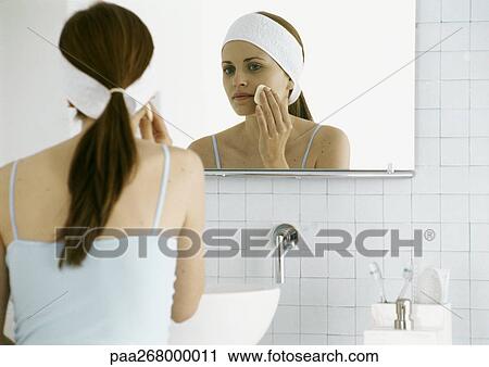 Woman washing face in front of mirror View Large Photo Image Stock Image - Woman washing face in front of mirror. Fotosearch
