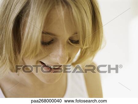 Young woman smiling with eyes down, close-up View Large Photo Image Stock Image - Young woman smiling with eyes down, close-up. Fotosearch