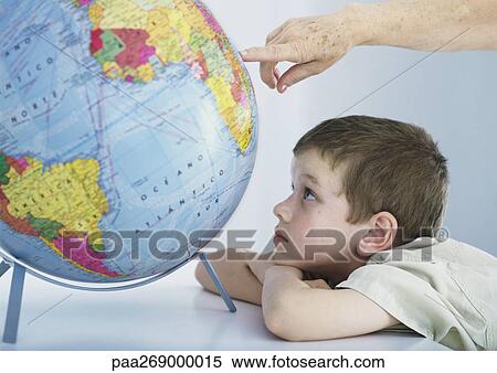 Boy looking at globe, elderly person's hand pointing to spot on globe View Large Photo Image Stock Photography - Boy looking at globe, elderly person's hand pointing to spot on globe. Fotosearch