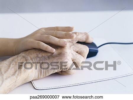 Stock Photo - Boy's hand on elderly woman's holding computer mouse. Fotosearch