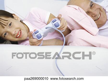 Stock Image - Girl holding joystick next to grandfather. Fotosearch