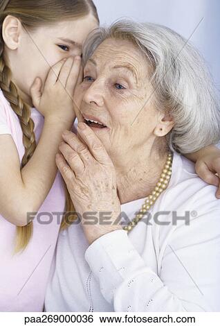 Girl whispering to grandmother View Large Photo Image Stock Photograph - Girl whispering to grandmother. Fotosearch