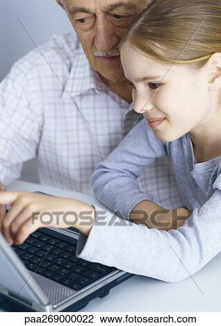 Stock Image - Grandfather and girl looking at laptop computer. Fotosearch