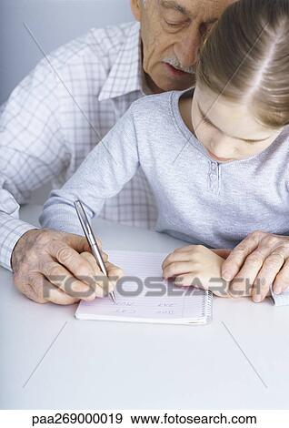 Grandfather helping girl write in notebook View Large Photo Image Stock Photo - Grandfather helping girl write in notebook. Fotosearch