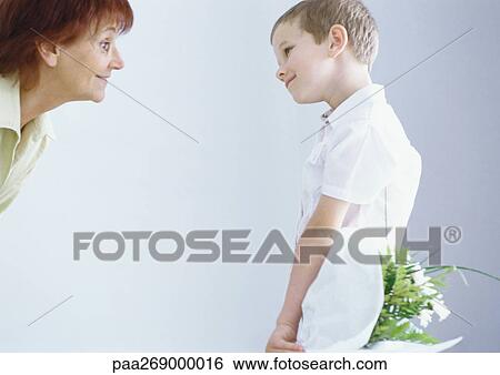 Grandmother with boy holding flowers behind his back View Large Photo Image Stock Photograph - Grandmother with boy holding flowers behind his back. Fotosearch