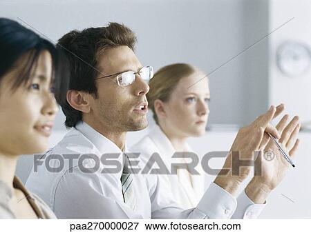 Business people in meeting, man with glasses gesturing View Large Photo Image Stock Photo - Business people in meeting, man with glasses gesturing. Fotosearch