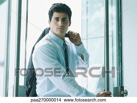 Businessman holding suit jacket over shoulder, coming through door View Large Photo Image Picture - Businessman holding suit jacket over shoulder, coming through door. Fotosearch