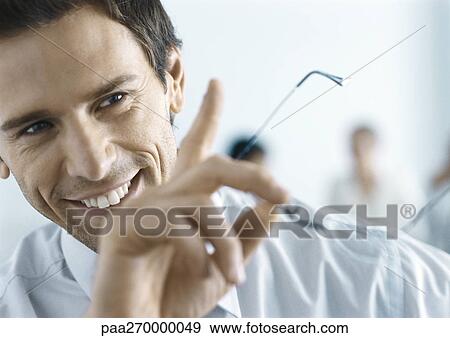 Businessman smiling, holding glasses, gesturing View Large Photo Image Stock Photo - Businessman smiling, holding glasses, gesturing . Fotosearch