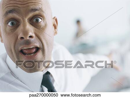 Businessman with eyebrows raised and mouth open pointing into background, close-up View Large Photo Image Stock Image - Businessman with eyebrows raised and mouth open pointing into background, close-up. Fotosearch