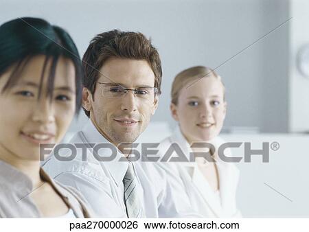 Businesspeople lined up, smiling at camera View Large Photo Image Stock Photograph - Businesspeople lined up, smiling at camera. Fotosearch