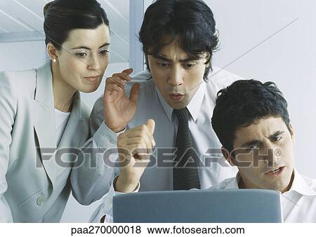 Stock Photo - Businesspeople looking down at computer screen gesturing and making faces. Fotosearch