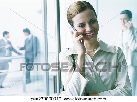 Businesswoman talking on cell phone, businesspeople in background View Large Photo Image Stock Image - Businesswoman talking on cell phone, businesspeople in background. Fotosearch