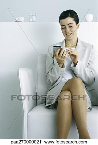 Woman sitting working on electronic organizer, legs crossed View Large Photo Image Stock Image - Woman sitting working on electronic organizer, legs crossed. Fotosearch