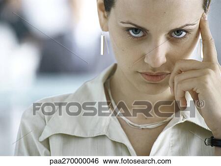 Stock Photograph - Woman with hand next to face, looking at camera. Fotosearch