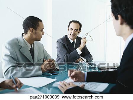 Stock Photo - Business people sitting around table having meeting. Fotosearch
