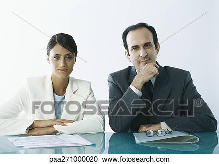 Businessman and businesswoman sitting at table with documents View Large Photo Image Stock Image - Businessman and businesswoman sitting at table with documents. Fotosearch