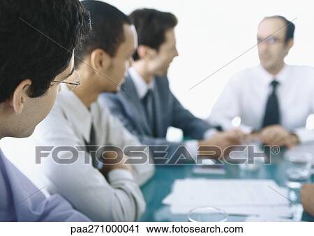 Businessmen sitting around table having meeting View Large Photo Image Stock Image - Businessmen sitting around table having meeting. Fotosearch
