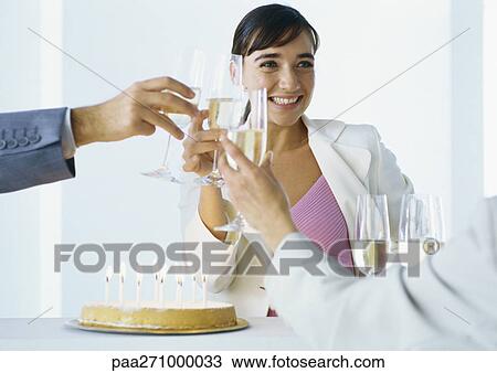 Stock Image - Businesspeople clinking glasses of champagne over birthday cake. Fotosearch