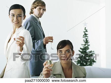 Businesspeople raising champagne flutes with christmas tree in background View Large Photo Image Stock Image - Businesspeople raising champagne flutes with christmas tree in background. Fotosearch